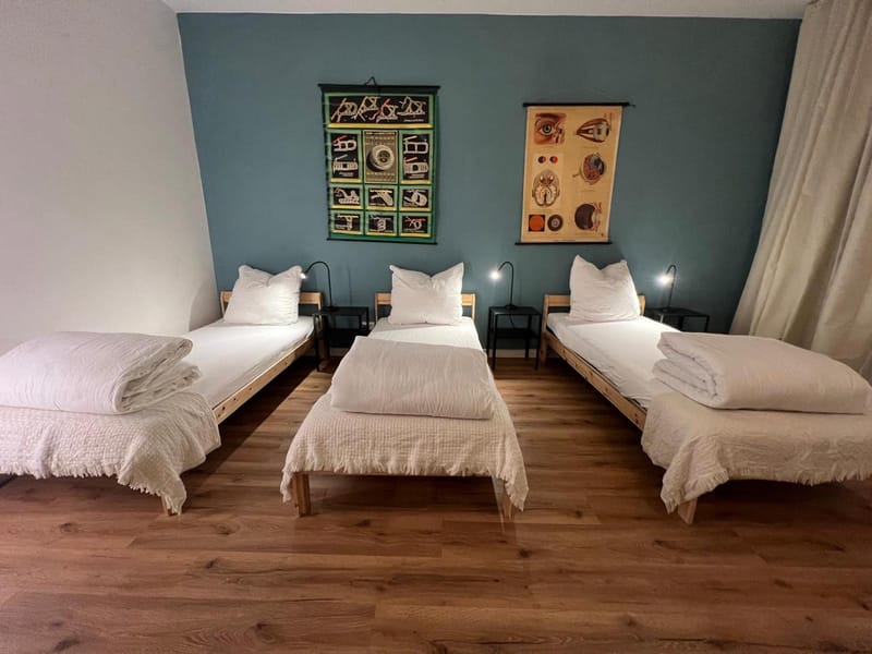 Dreibettzimmer mit Vintage-Lehrtafeln an petrolfarbener Wand in den Emmas Apartments