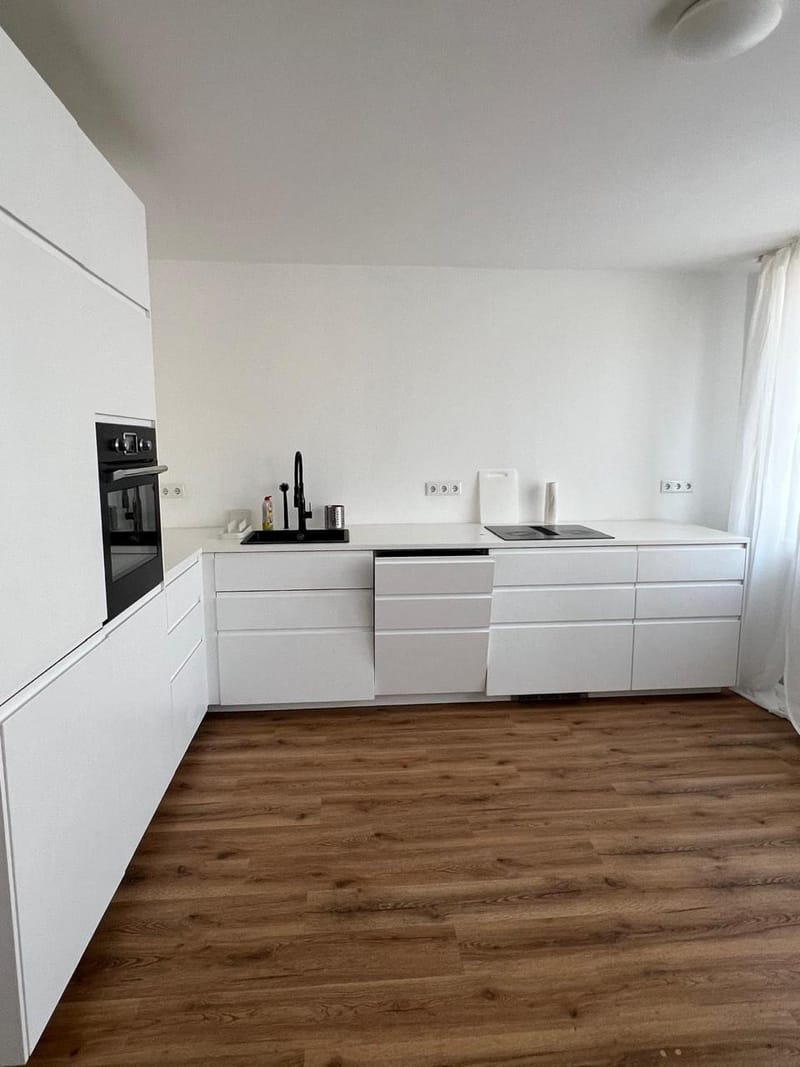 Weiße grifflose Küche mit schwarzem Backofen in den Emmas Apartments