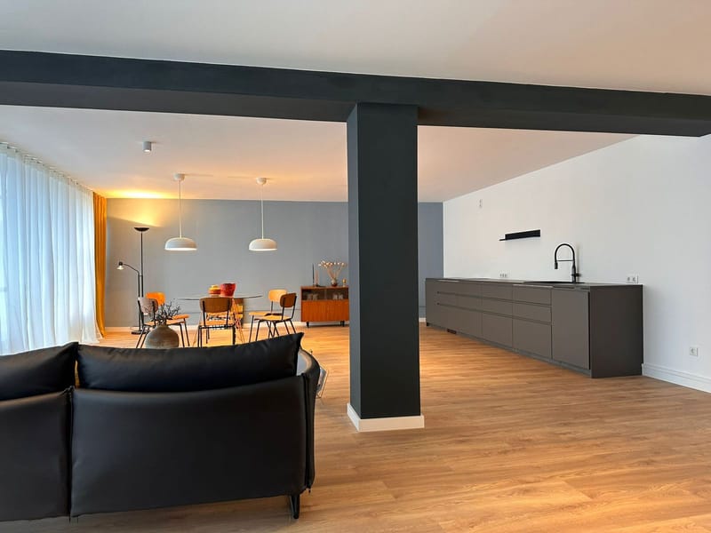 Offenes Loft mit Ledersofa und Stahlstütze