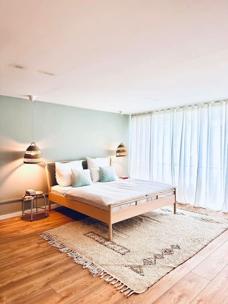 Schlafzimmer mit salbeigrüner Wand und Korb-Pendelleuchten