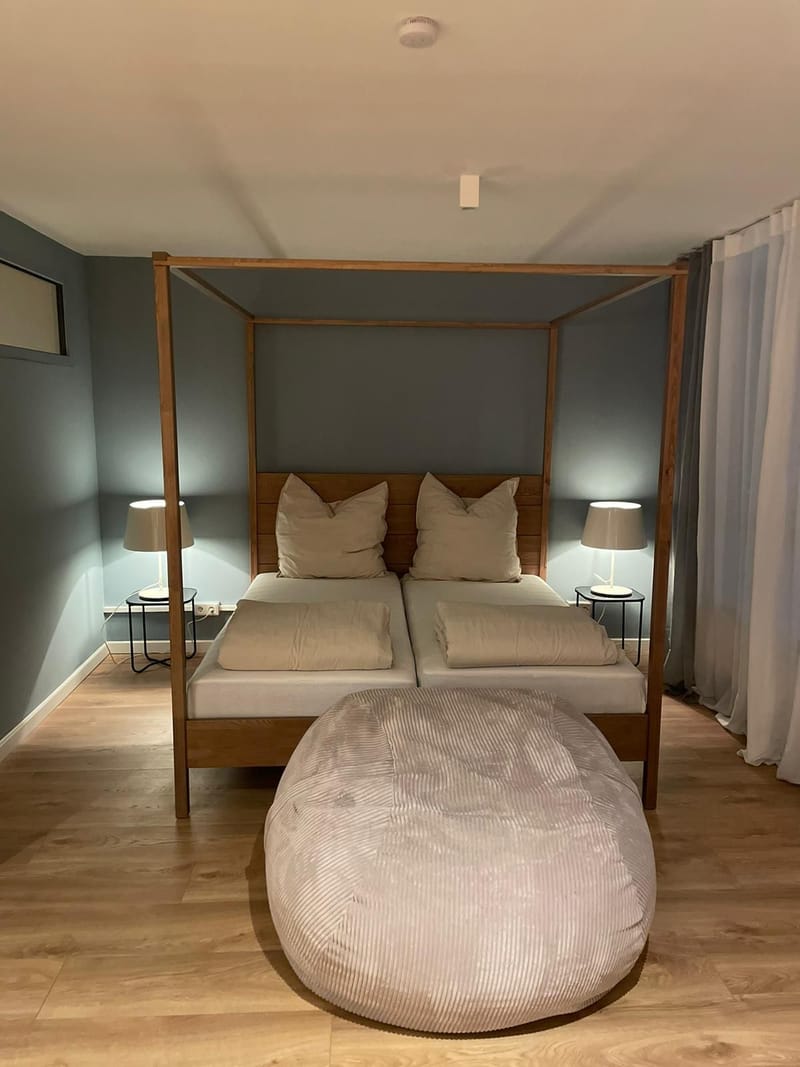 Himmelbett vor graublauer Wand mit Cord-Sitzsack